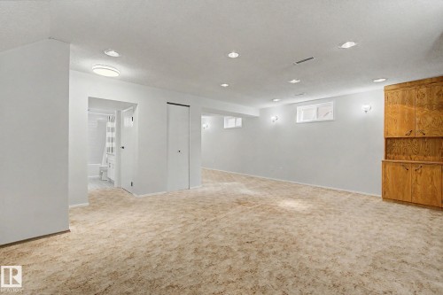 Carpeted open-concept room featuring recessed lighting, a built-in wood-finish cabinet, and a visible doorway to a full bathroom with a shower-over-tub - 170 Westridge Rd, Edmonton, AB - Indoor Photo Showing Other Room