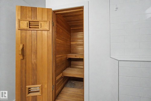 Built-in sauna featuring slatted wood paneling, multiple tiers of benches, a wood-slatted door with integrated vents, and a coordinating wood handle - 170 Westridge Rd, Edmonton, AB - Indoor Photo Showing Other Room