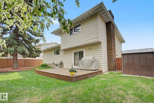 Rear exterior featuring neutral siding, a brick chimney, and a ground-level deck - 170 Westridge Rd, Edmonton, AB - Outdoor