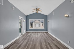 Vaulted ceiling room featuring wood-finish flooring, a ceiling fan, and a transom window - 