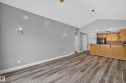 Spacious living area featuring wood-finish flooring, vaulted ceilings, and sconce lighting - 