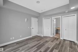 Spacious room featuring wood-finish flooring, light gray walls, and white baseboards - 