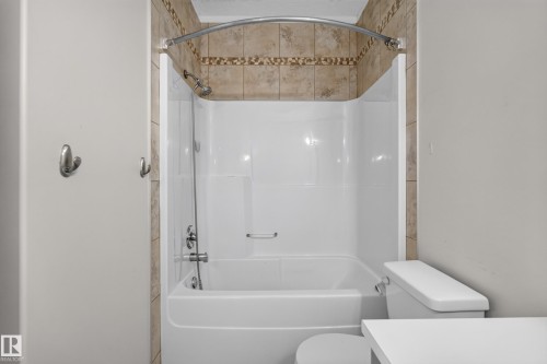Full bathroom featuring a shower-over-tub combination with a curved shower rod and a tiled surround - 18 2565 Hanna Crescent, Edmonton, AB 