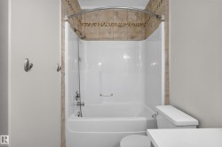Full bathroom featuring a shower-over-tub combination with a curved shower rod and a tiled surround - 