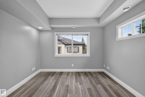 Light-filled room featuring wood-finish flooring, recessed lighting, two distinct windows, and a dropped ceiling detail - 18 2565 Hanna Crescent, Edmonton, AB 