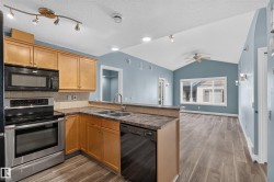Open-concept kitchen with wood-finish flooring and light wood cabinetry - 