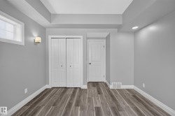 Interior room featuring wood-finish flooring, light gray walls, and white baseboards - 