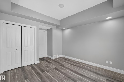 Room featuring wood-finish flooring, recessed lighting, bi-fold closet doors, and light gray wall paint with white trim - 18 2565 Hanna Crescent, Edmonton, AB 