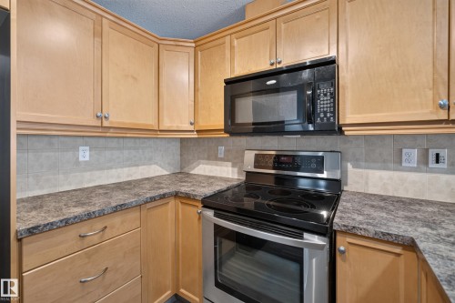 Kitchen featuring light wood cabinetry, a built-in microwave, a stainless steel electric range, and laminate countertops - 18 2565 Hanna Crescent, Edmonton, AB 