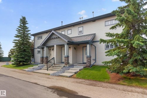 Duplex exterior with light siding, dark trim, and stone-wrapped porch columns - 18 2565 Hanna Crescent, Edmonton, AB 