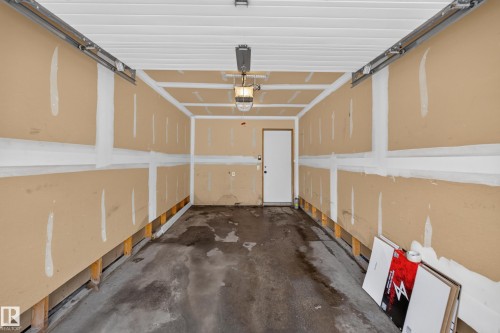 Attached single-car garage featuring a concrete floor, exposed wall studs, and an overhead garage door opener - 18 2565 Hanna Crescent, Edmonton, AB 