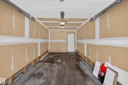 Attached single-car garage featuring a concrete floor, exposed wall studs, and an overhead garage door opener - 