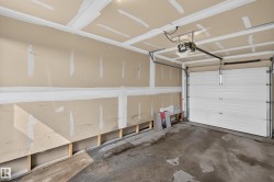 Attached garage with exposed drywall, concrete flooring, and a sectional overhead door - 