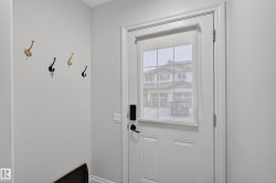 Entryway featuring a white paneled door with integrated window and privacy blind, smart lock hardware, and light gray wall paint - 