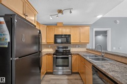 Kitchen featuring wood-finish cabinetry, stainless steel appliances, a double basin sink, and a breakfast bar - 