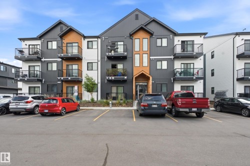 Contemporary multi-story building featuring dark gray and white siding with natural wood-tone accents - 106 856 Secord Boulevard Nw, Edmonton, AB 
