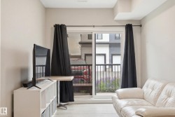 Sliding glass door opening to an exterior balcony with black metal railing and visible landscaping - 
