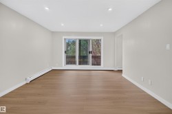 Spacious room featuring wood-finish flooring, light grey walls, and recessed ceiling lighting - 