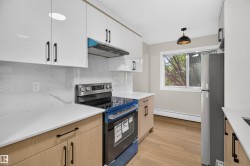 Contemporary kitchen featuring two-tone cabinetry, stone countertops, a full-height backsplash, stainless steel appliances, and wood-finish flooring - 