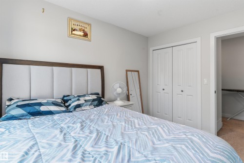 Bedroom featuring a paneled headboard with wood-finish trim, light gray wall paint, and white bi-fold closet doors - 170 804 Welsh Drive, Edmonton, AB 