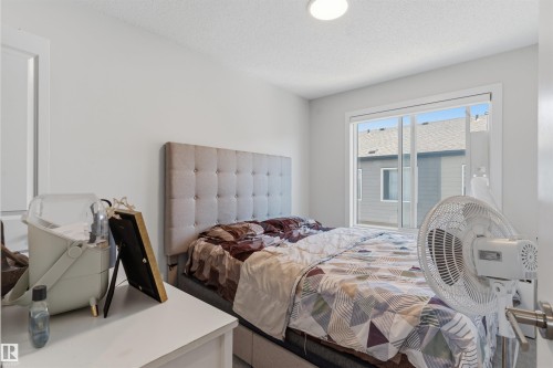 Bedroom featuring a sliding window, white walls, and a flush-mount ceiling light - 170 804 Welsh Drive, Edmonton, AB 