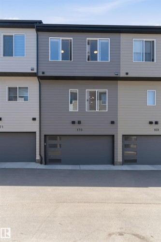 Modern townhome exterior featuring multi-toned siding, a contemporary garage door with frosted glass panels, and multiple windows across two levels - 170 804 Welsh Drive, Edmonton, AB 