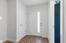 Entryway featuring wood-finish flooring, a white paneled door with brushed nickel hardware, and a main entry door with a vertical frosted glass insert - 170 804 Welsh Drive, Edmonton, AB 