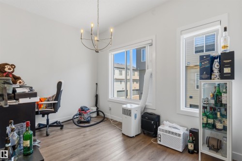 Bright room featuring multiple windows, wood-finish flooring, a contemporary chandelier, and a neutral wall palette - 170 804 Welsh Drive, Edmonton, AB 