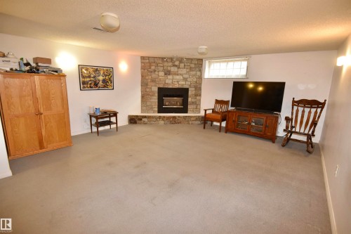 Stone fireplace featuring a black firebox and hearth - 7923 94 Avenue Nw, Edmonton, AB 