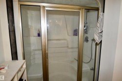 Shower enclosure with framed glass doors, integrated shelving, a shower wand and a steam shower - 