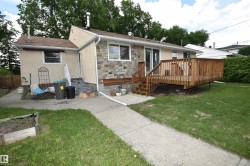Rear exterior featuring a spacious wooden deck with railings, stone facade accents, and stucco siding - 