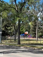 Adjacent community park featuring a basketball hoop, playground equipment, and mature trees - 