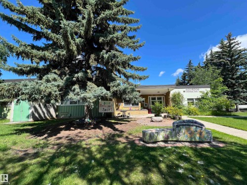 Single-story building with a flat roofline, featuring light-colored exterior walls and green paneling - 7923 94 Avenue Nw, Edmonton, AB - Outdoor