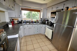 Kitchen featuring light-toned cabinetry with dark hardware, dark countertops, and stainless steel appliances - 