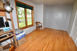 Hardwood flooring throughout the room, featuring a large window with wood trim - 