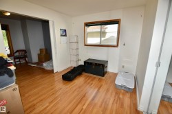Has sliding pocket doors to adjoining bedroom, which could be used as a den or nursery. Bright interior space featuring wood-finish flooring, a window with wood trim, and white walls - 