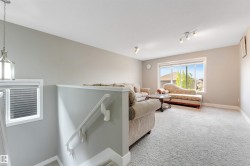 Upper-level living space featuring a large window, track lighting, and a neutral color palette - 