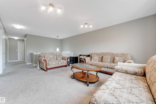 Spacious carpeted room featuring track lighting and a pendant light fixture - 5930 19A Avenue, Edmonton, AB 