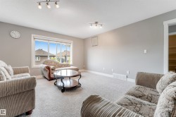 Carpeted living space featuring a large picture window, track lighting, and a white baseboard trim - 