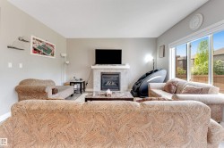 Living area featuring a fireplace with a tiled surround and mantle, wood-finish flooring, light grey walls, and a large sliding glass door - 