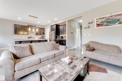 Open-concept living area featuring wood-finish flooring, recessed lighting, and a modern kitchen - 
