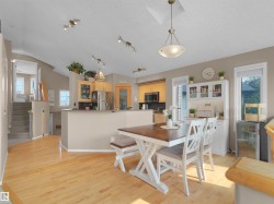 Open-concept kitchen and dining area featuring light wood-finish flooring, a vaulted ceiling, and recessed lighting - 
