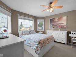 Recessed sleeping area featuring multiple window openings, a ceiling fan with integrated lighting, and neutral wall tones - 