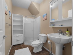Full bathroom featuring a corner shower with glass enclosure, white pedestal sink, and coordinating white toilet - 