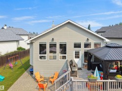 Rear exterior featuring light gray siding, multiple windows, a white entry door, and an attached wood deck - 