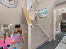 Multi-level interior featuring a carpeted staircase with light wood railings, a wall-mounted clock, and dark tile flooring - 