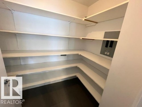 Spacious walk-in pantry with ample white shelving, dark flooring, and a contemporary door handle - 1101 10011 123 Street, Edmonton, AB 