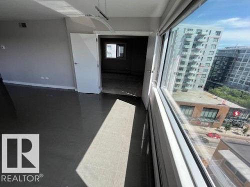 Spacious room featuring large windows, a contemporary light fixture, and light gray walls - 1101 10011 123 Street, Edmonton, AB 