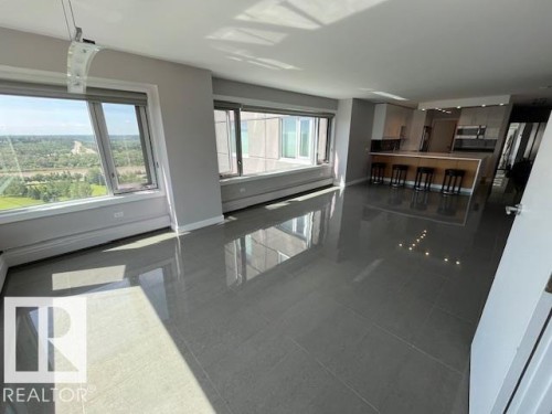 Open-concept living area featuring large windows, high ceilings, polished tile flooring, and integrated kitchen cabinetry - 1101 10011 123 Street, Edmonton, AB 