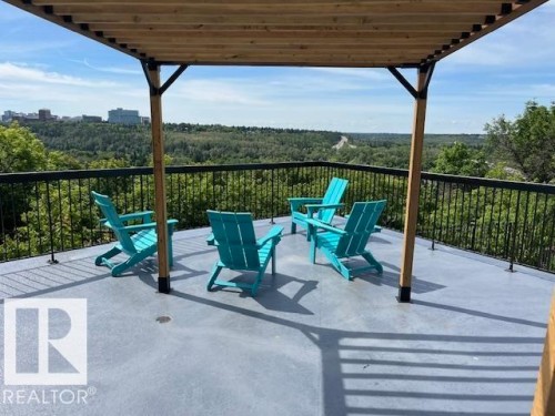 Spacious outdoor deck featuring a wooden pergola, black metal railings, and a concrete-finish surface - 1101 10011 123 Street, Edmonton, AB 